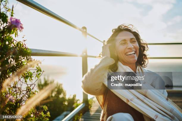 lachende reife frau sitzt bei sonnenuntergang am meer - older woman in nature stock-fotos und bilder