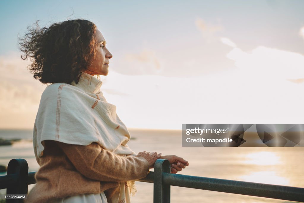 Reife Frau beobachtet den Sonnenuntergang über dem Ozean