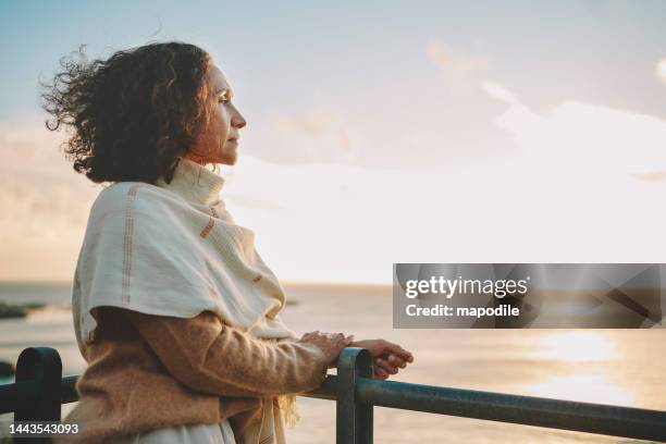 femme mûre regardant le coucher de soleil sur l’océan - introspection photos et images de collection