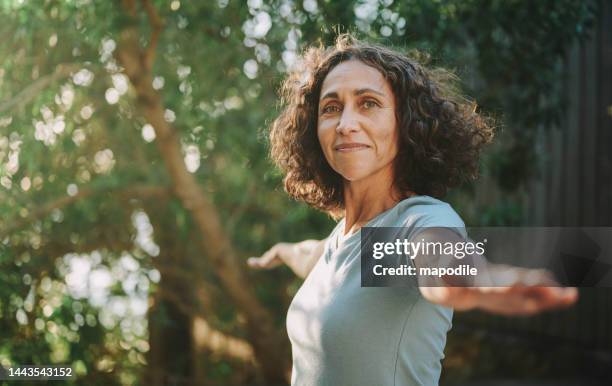 femme mûre souriante faisant du yoga dehors dans un parc en été - yoga pose photos et images de collection