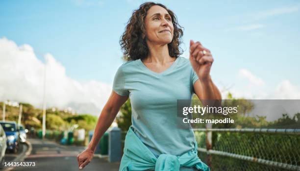 smiling mature woman out for a power walk in summer - walking through door stockfoto's en -beelden