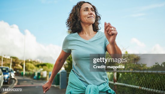 Smiling mature woman out for a power walk in summer Smiling mature woman out for a power walk in summer
