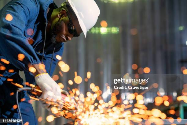 industrial worker in a factory with electric grinder tools to grinding surface on metal workpiece. - équipement de construction photos et images de collection