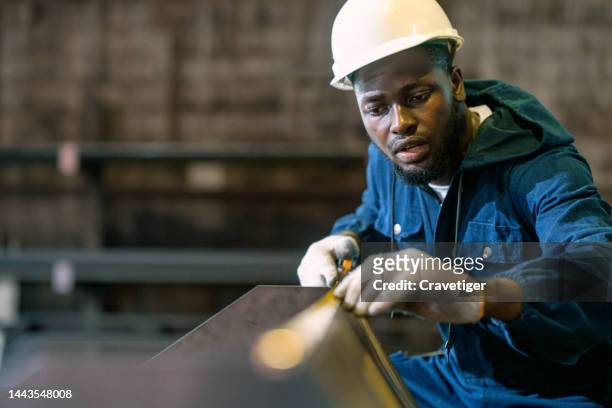 african worker is measuring the length of metal in the factory workshop. - foundry methodist church foto e immagini stock