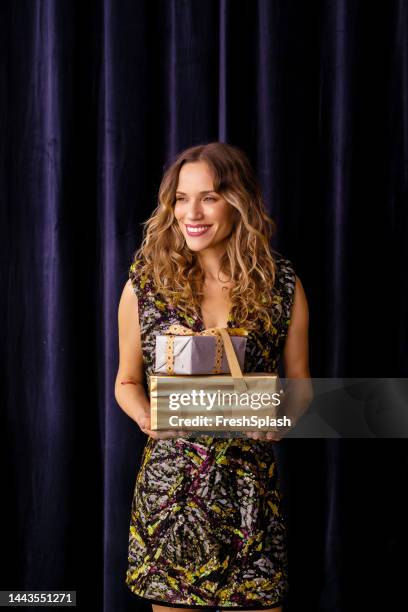 a happy woman holding beautifully wrapped birthday presents whil - woman ribbon happy stockfoto's en -beelden