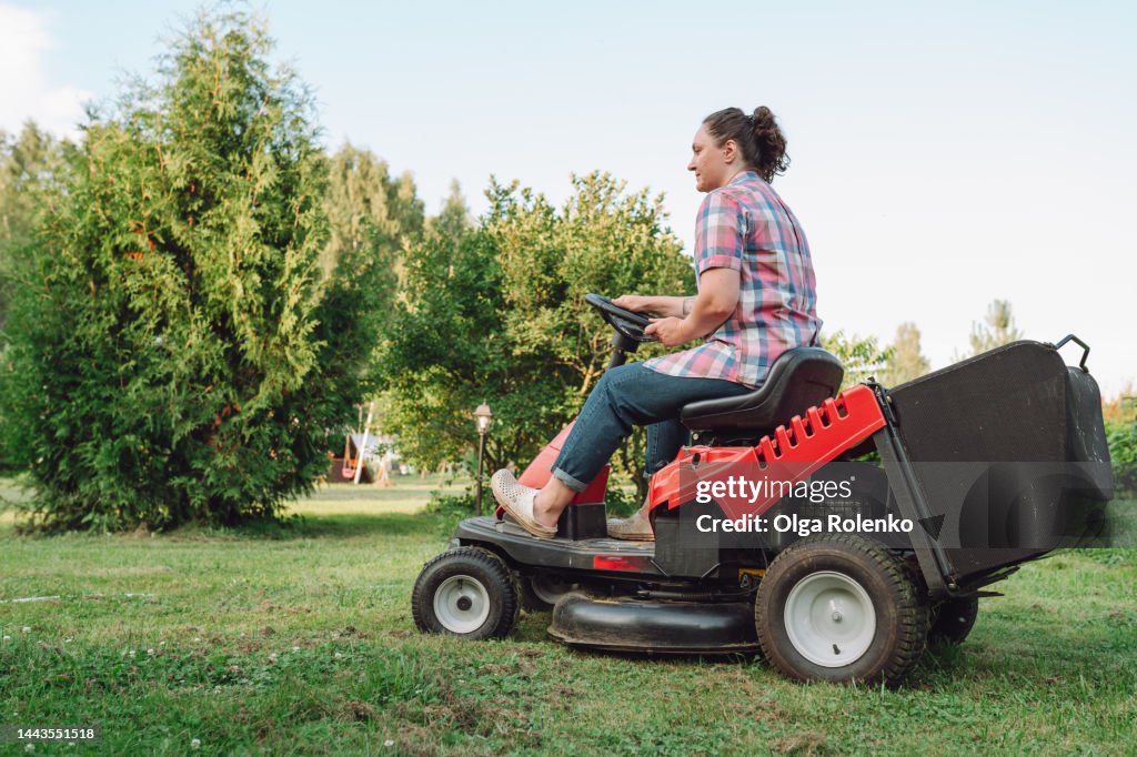 Tractor lawn mower. A woman is mowing grass with a tractor on her lawn