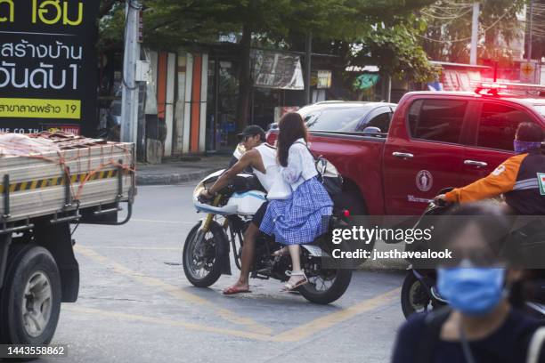 adult thai couple on motorcycle on busy intersection in bangkok chatuchak. - flash back stock pictures, royalty-free photos & images