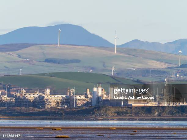 wind turbines bewhind a large gas plant from walney island, barrow in furness, cumbria, uk. - barrow in furness stock-fotos und bilder