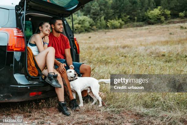 joven pareja de excursionistas acariciando a su perro al aire libre - sunday in the valley fotografías e imágenes de stock