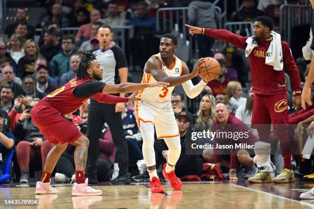 Aaron Holiday of the Atlanta Hawks passes while under pressure from Darius Garland of the Cleveland Cavaliers at Rocket Mortgage Fieldhouse on...