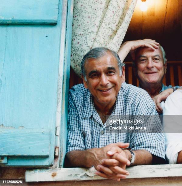 Indian film director and producer Ismail Merchant and American director James Ivory pose, looking through window during the filming of the former's...