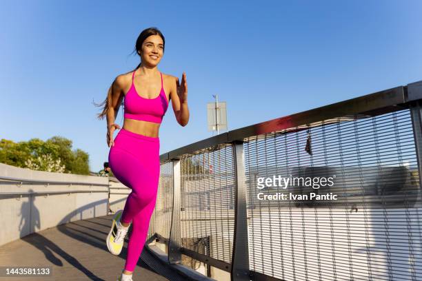 female athlete running on a footbridge - runner warming up stock pictures, royalty-free photos & images