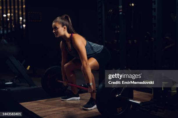 young woman lifting barbell at gym - women's weightlifting stock pictures, royalty-free photos & images