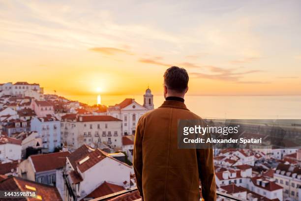 rear view of a man looking at lisbon skyline at sunrise, portugal - lisbon stock pictures, royalty-free photos & images
