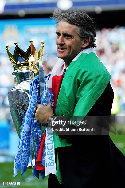 Roberto Mancini the manager of Manchester City celebrates with the trophy following the Barclays Premier League match between Manchester City and...