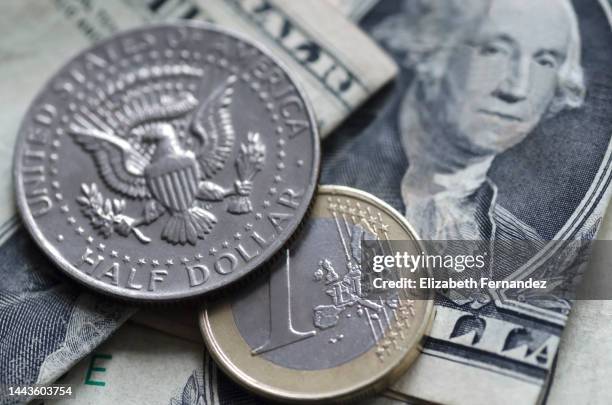 extreme close up of a half dollar coin and a one euro coin on dollar bills background. money concept. - moneta da un euro foto e immagini stock