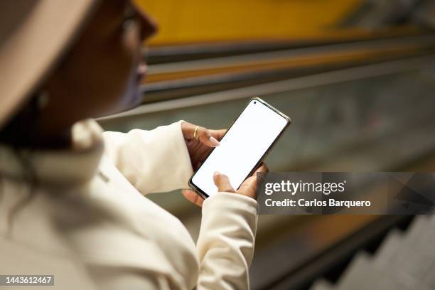 close up photo of black woman using phone while descending escalators at subway. - metro madrid stock pictures, royalty-free photos & images