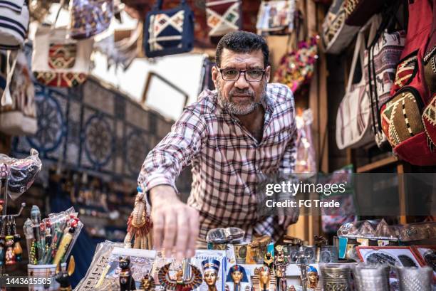 portrait d’un propriétaire d’entreprise arrangeant des souvenirs dans son magasin - egypt souvenirs photos et images de collection