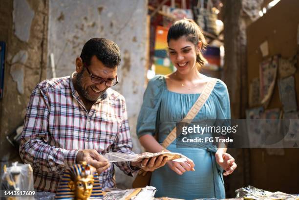 salesman selling to female customer in a souvenir store - cairo stock pictures, royalty-free photos & images