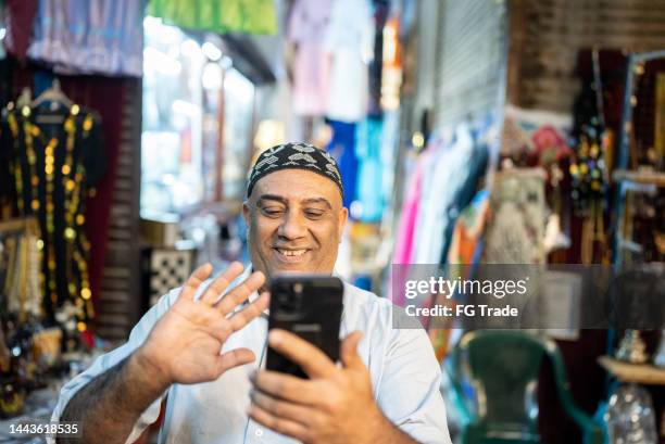 mature man doing a video call on smartphone outdoors - egyptian people stock pictures, royalty-free photos & images