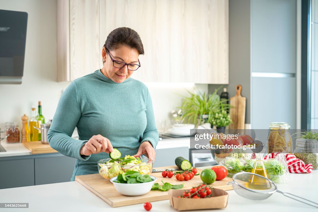 Mature woman preparing healthy vegetables salad