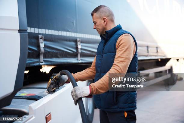 semi-camion che viene rifornito dal camionista adulto medio - fare il pieno di benzina foto e immagini stock