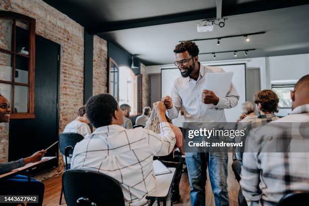 teacher greeting student in classroom - teacher stockfoto's en -beelden