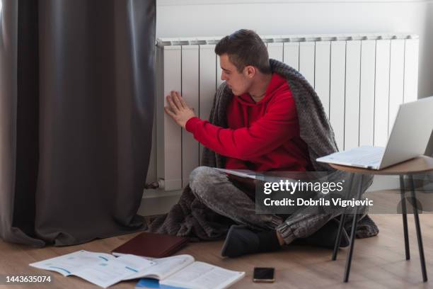 student sitting by radiator and checking the thermostat - poor concentration stock pictures, royalty-free photos & images