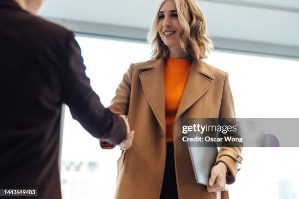 two businesswomen making business deal with handshake - business deal stockfoto's en -beelden