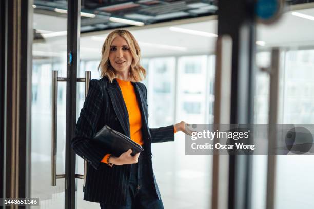 young female estate agent showing client a modern office rental - woman opening door stock pictures, royalty-free photos & images