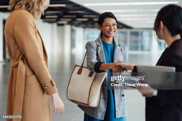 smiling asian female estate agent sealing a deal with clients for new office space rental - real estate developer stock pictures, royalty-free photos & images
