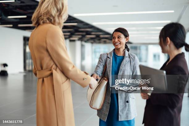 smiling asian female estate agent sealing a deal with clients for new office space rental - real estate developer stock pictures, royalty-free photos & images