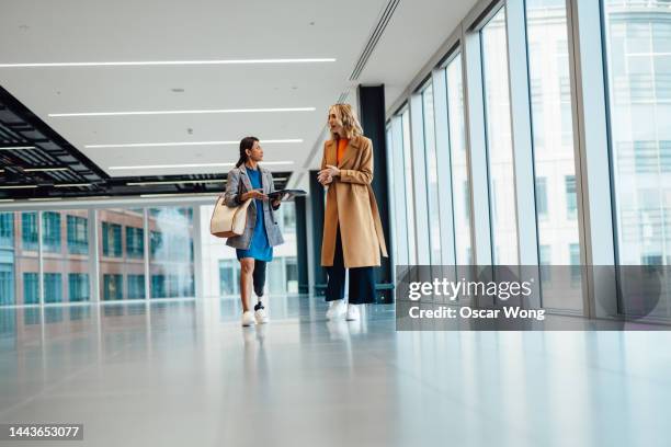 asian real estate agent showing an empty office building to a female entrepreneur - property developer stock pictures, royalty-free photos & images