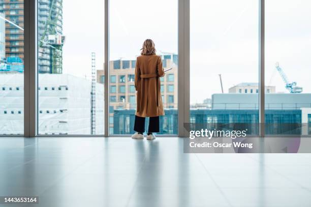 businesswoman looking out window in meeting room - transgender foto e immagini stock
