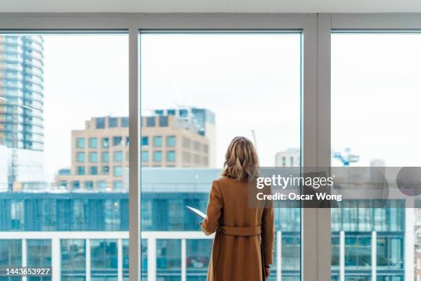 businesswoman looking out window in meeting room - man looking out of window stock-fotos und bilder