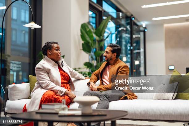 multi ethnic group sharing ideas in office lobby - lobby stock pictures, royalty-free photos & images