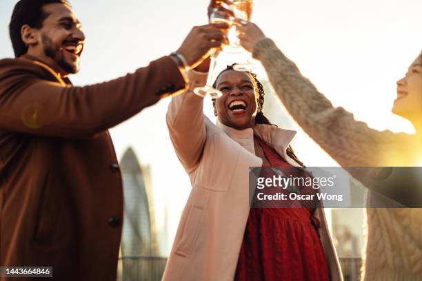 business people toasting champagne flutes while celebrating christmas at rooftop against london cityscape - reünie sociaal stockfoto's en -beelden