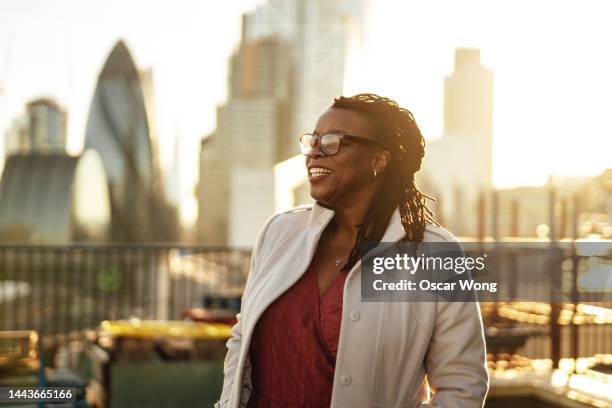 smiling female entrepreneur standing at rooftop garden against london city skyline - corporate skyline stock pictures, royalty-free photos & images