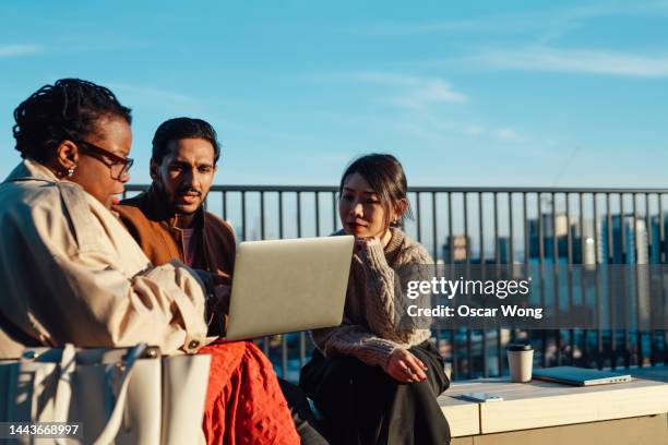 coworkers working on laptop at rooftop garden in a high-rise office building - colleagues stock pictures, royalty-free photos & images