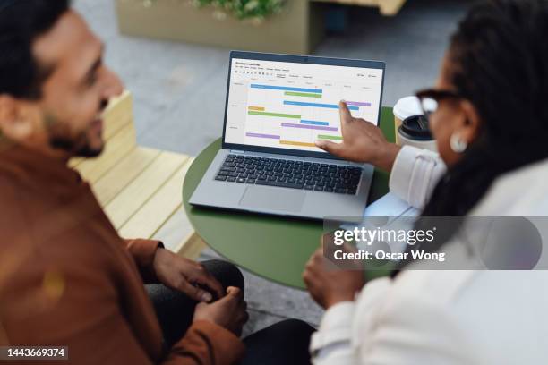 over the shoulder view of coworkers discussing project and having work meeting at rooftop garden in high-rise office building - mapa-de-carreteras fotografías e imágenes de stock