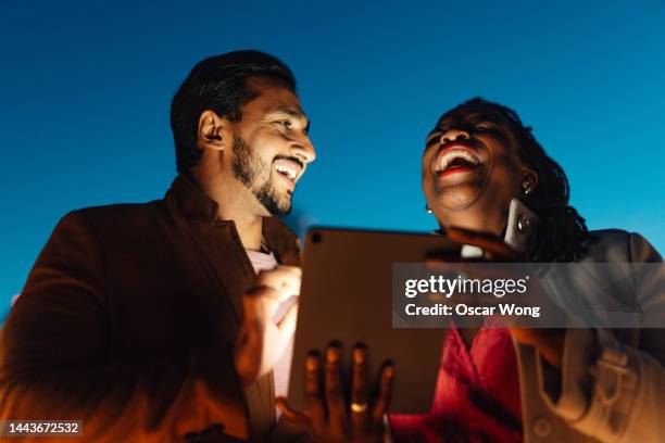 close-up shot of two adults using digital tablet watching video against dark blue sky - film lighting equipment stock pictures, royalty-free photos & images