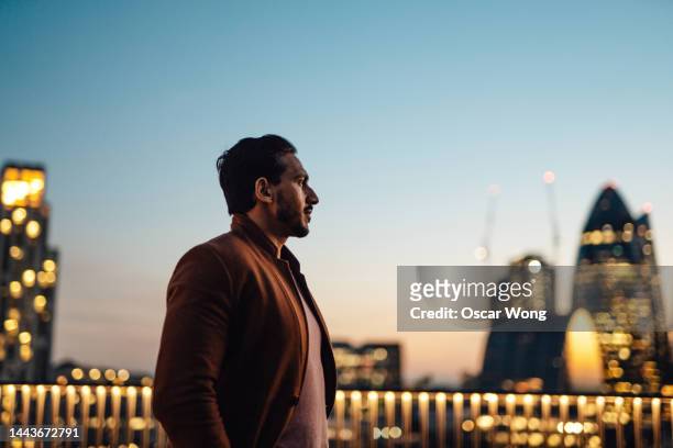 businessman looking over city at rooftop in high-rise business building - high rise night stockfoto's en -beelden