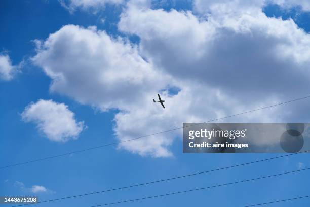 photograph taken from below towards the blue sky with white clouds at the moment that a plane passes in mid-flight you can see the wiring of the electrical wiring in place - flugzeug seitlich himmel stock-fotos und bilder