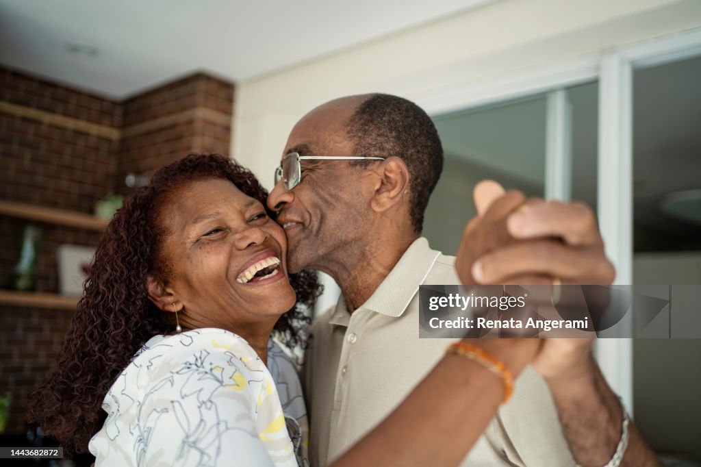 African American senior couple dancing on the balcony