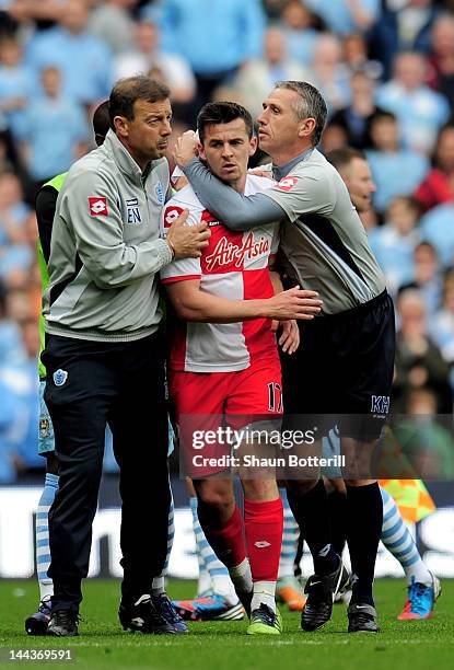 Joey Barton of QPR is restrained by QPR First Team Coach Eddie Niedzwiecki and QPR Goalkeeping Coach Kevin Hitchcock after being shown the red card...