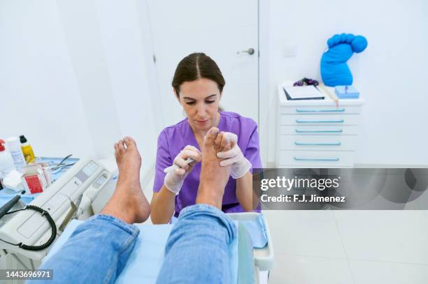 podiatrist curing patient callus in clinic - podiatrist stock pictures, royalty-free photos & images