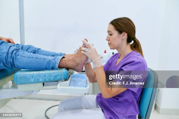 podiatrist curing patient callus in clinic - foot foto e immagini stock