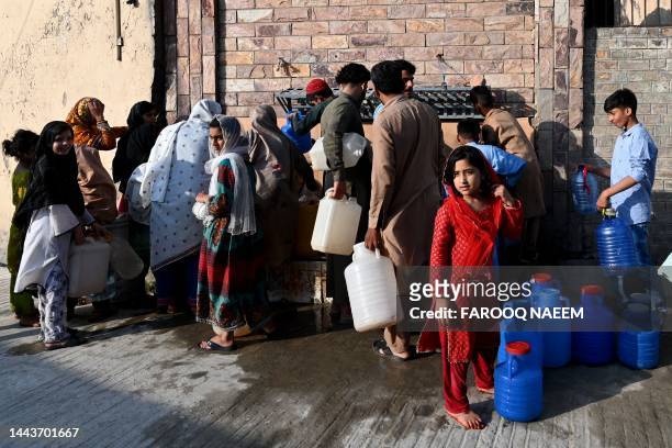 People gather to fetch drinking water from water supply taps, along a road in Rawalpindi on July 3, 2023.