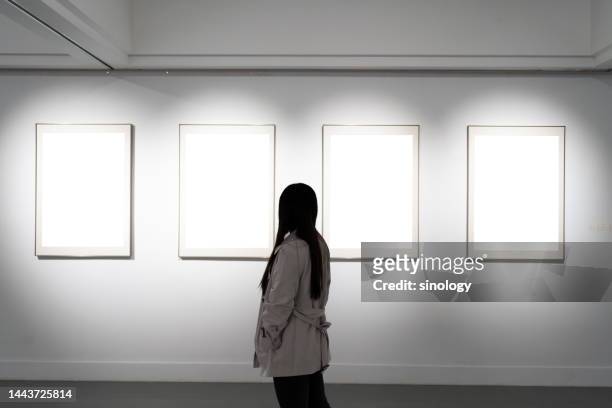 young woman looking at paintings in art gallery - museum frame stock pictures, royalty-free photos & images