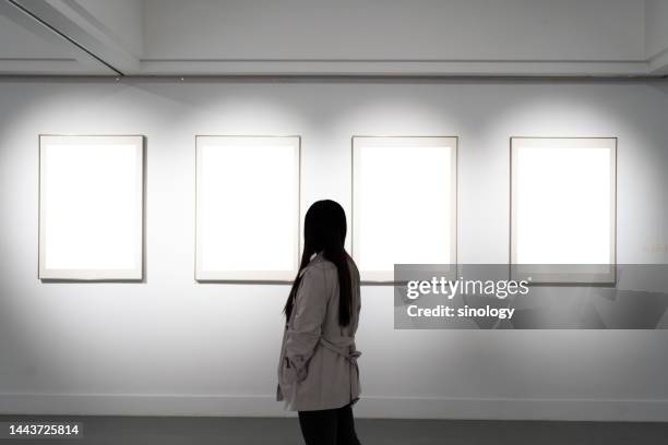 young woman looking at paintings in art gallery - gallery imagens e fotografias de stock